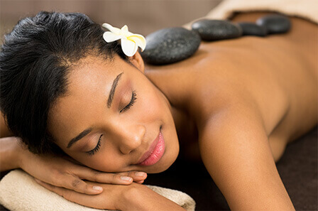 A woman laying down receiving a hot stone treatment at a spa