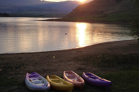4 kayaks lined up on the bank of a dam