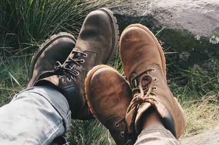 A close up of two hikers shies as they sit with their legs crossed