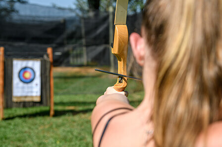 A women takes aim at a target with a bow and arrow